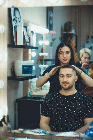 Hairdresser makes a fashionable haircut to a man in the salonの写真素材