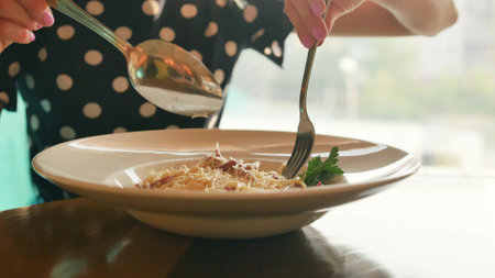 Woman eating spaghetti carbonara in a restaurant. Close-up.の写真素材