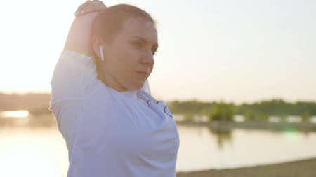 Woman playing sports outdoors. Stretching the arms. Warm-up before playing sports.の写真素材