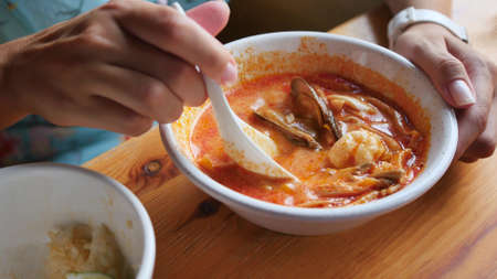 Pretty woman eating thai tom yam soup in a restaurantの写真素材