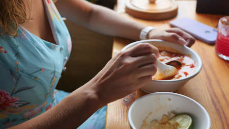 Pretty woman eating thai tom yam soup in a restaurantの写真素材