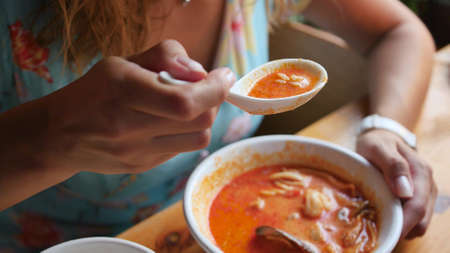 Pretty woman eating thai tom yam soup in a restaurantの写真素材