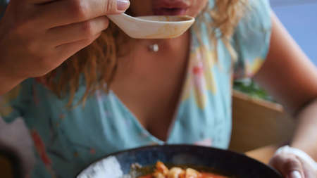 Pretty woman eating thai tom yam soup in a restaurant