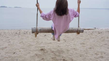Young relaxing asian woman enjoying the feeling of freedom and fresh air, swinging on a swing near...