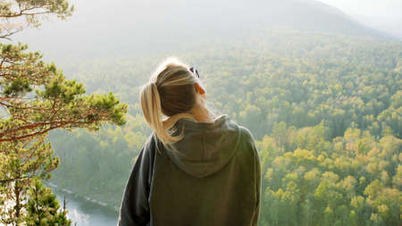 A woman traveler stands on the top of a mountain near the banks of the Mana River in Siberia and enjoys a beautiful view.の写真素材