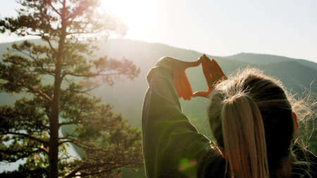 A woman traveler stands on the top of a mountain near the banks of the Mana River in Siberia and enjoys a beautiful view.の写真素材
