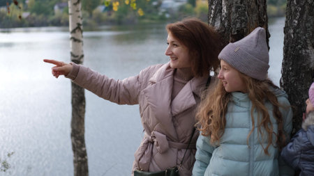 Mom and daughter stand on the shore of the lake during an autumn walk.の写真素材