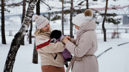 Two lovely women laugh and hug against the background of a snowy winter park. female friendship conceptの写真素材