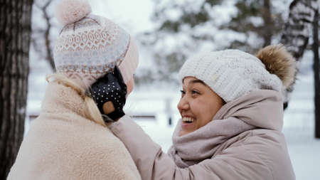 Two lovely women laugh and hug against the background of a snowy winter park. female friendship conceptの写真素材