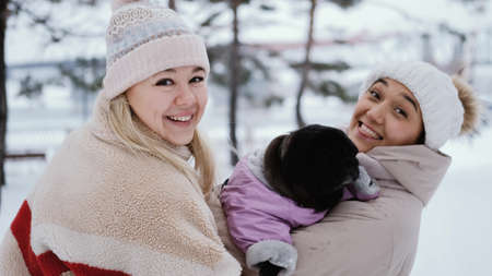 Two lovely women laugh and hug against the background of a snowy winter park. female friendship...
