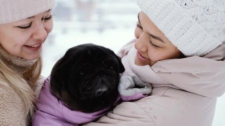 Two lovely women laugh and hug against the background of a snowy winter park. female friendship conceptの写真素材