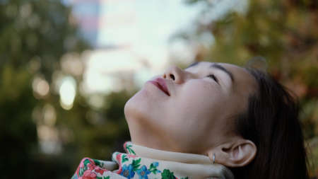 Happy smiling woman looking up to the sky and breathing fresh autumn air.の写真素材
