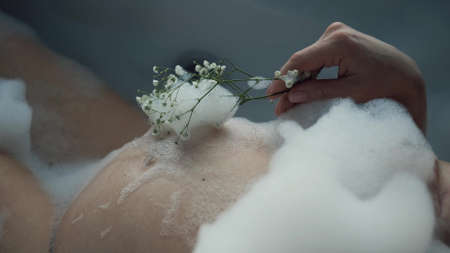 A pregnant woman is taking a bath. Close-up of a pregnant womans belly