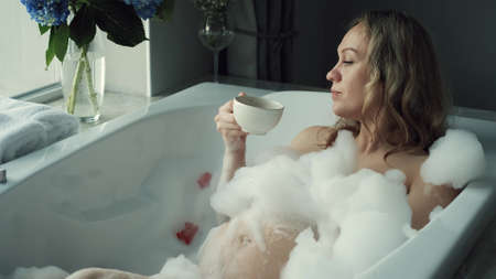 A pregnant woman is taking a bath. Close-up of a pregnant womans belly
