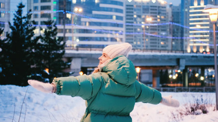 Young woman in winter clothes enjoys the evening lights of a cold cityの写真素材