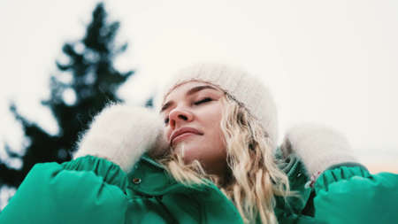 Young woman shaking off snow from winter clothes outdoors.の写真素材