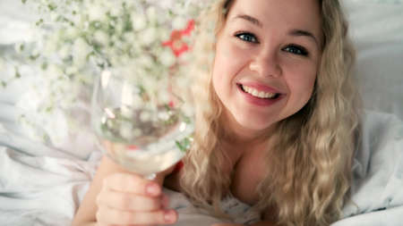 A caucasian woman in red lingerie lies on the blood with a glassの写真素材
