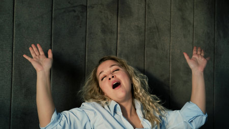 Portrait of a beautiful young woman stretching and yawning while waking up in the morningの写真素材