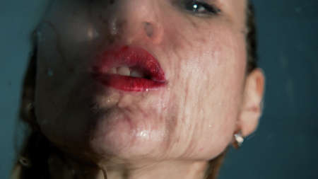 A beautiful girl with red lipstick on her lips enjoys under the shower.の写真素材