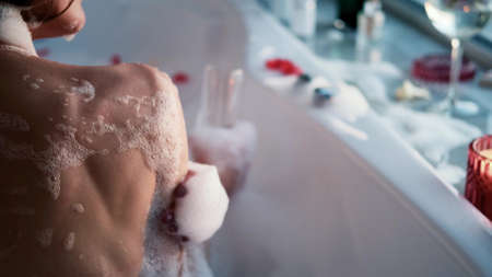 Close-up of a relaxed woman in a bubble bath. A woman takes a bath near the window on a cloudy day. The concept of mental health.の写真素材