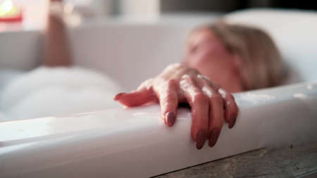Close-up of a relaxed woman in a bubble bath. A woman takes a bath near the window on a cloudy day. The concept of mental health.の写真素材