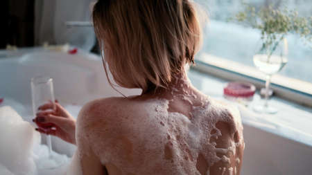 Close-up of a relaxed woman in a bubble bath. A woman takes a bath near the window on a cloudy day. The concept of mental health.の写真素材