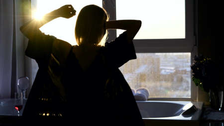 Woman dancing and drinking sparkling wine before taking a relaxing bathの写真素材