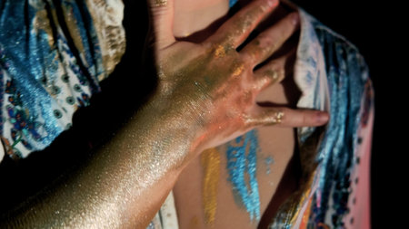 Paint a womans body. Close-up of womans hands in bright shiny paint. Body art.