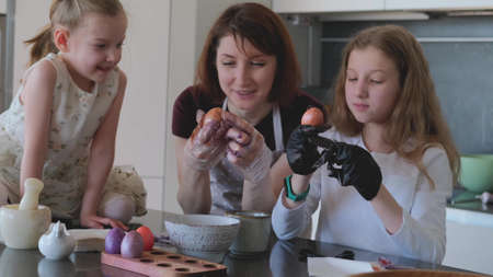 Happy Easter. Mom and two cute daughters paint eggs for the traditional spring holiday at homeの写真素材