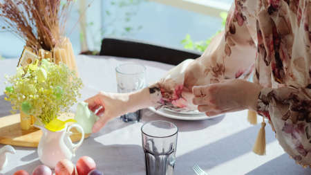 A woman in a smart dress serves a festive Easter table