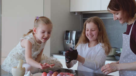 Happy Easter. Mom and two cute daughters paint eggs for the traditional spring holiday at home