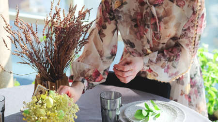 A woman in a smart dress serves a festive Easter table