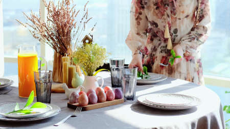 A woman in a smart dress serves a festive Easter table