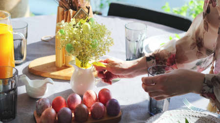 A woman in a smart dress serves a festive Easter table