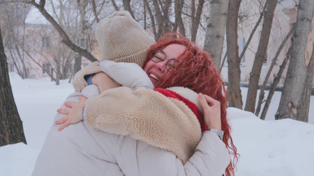 Happy women hug and laugh during a long-awaited meeting outdoors in winter. Two women with joy and laughter hug each other and laughの写真素材