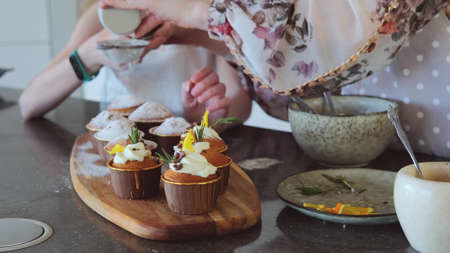 Little girl and mom are preparing cupcakes in the kitchen. slow motion.