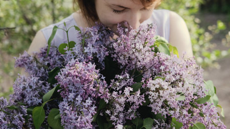 A large basket with garden fresh spring flowers in the hands of a woman. A bouquet of lilacs with a krypny plan.の写真素材