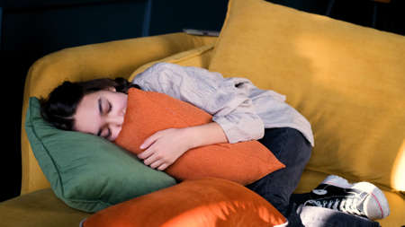 Frustrated introvert girl aged 13 lies on the couch at home and suffers from school discrimination or bullying. Unhappy sad teenager is experiencing psychological problems. The concept of a loner, an outcast.の写真素材