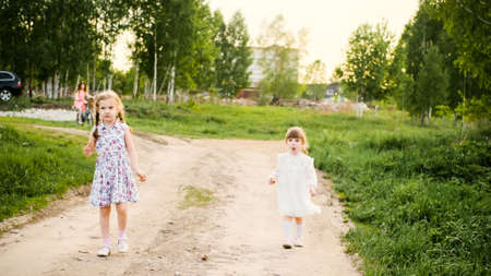 Happy children walk along a rural road in the light of the setting sunの写真素材