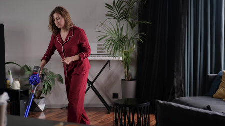 A woman dances with a vacuum cleaner. A young woman cleans her house, listens to music and expresses positive emotions - happy real people 4k footageの写真素材