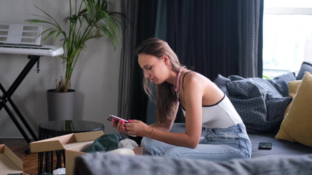Dissatisfied annoyed customer opens a cardboard box. Shocked young female consumer having a complaint about a problem, frustrated by the poor delivery of a purchase order after deliveryの写真素材