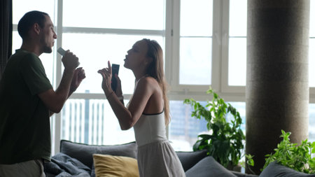 Young cheerful couple dancing and singing together at home. Husband and wife have fun and bondの写真素材