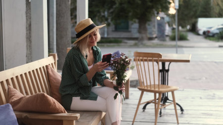 Portrait of a beautiful woman using a smartphone while sitting on a bench. A woman uses an app on her smartphoneの写真素材