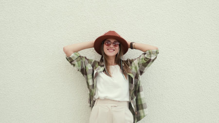 Happy fashionable beautiful woman in brown hat posing near white wall. The concept of summer holidays and great mood.の写真素材
