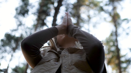 A woman enjoys a good atmosphere in nature raises her hands up to the sky with gratitudeの写真素材