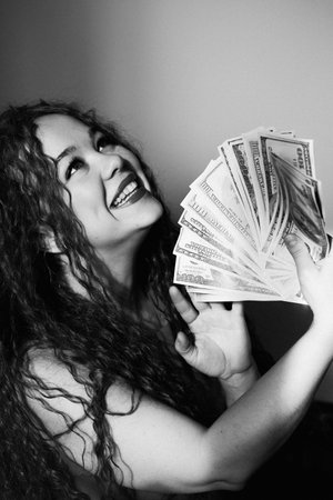 A rich red-haired woman holds a wad of dollars in her hand. Concept of financial successの写真素材