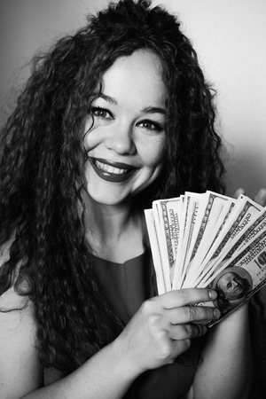 A rich red-haired woman holds a wad of dollars in her hand. Concept of financial successの写真素材
