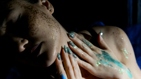 The face of a beautiful brunette is decorated with sparkles and bright paint. Body Art.の写真素材