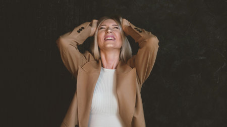 Portrait of an angry, angry and unhappy woman screaming loudly with palms up against a dark background. The woman symbolizes irritation, mental disorder.の写真素材
