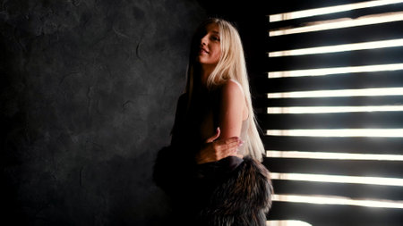 Portrait of a smiling glamorous young blonde woman in a dark room, which symbolizes inner freedomの写真素材